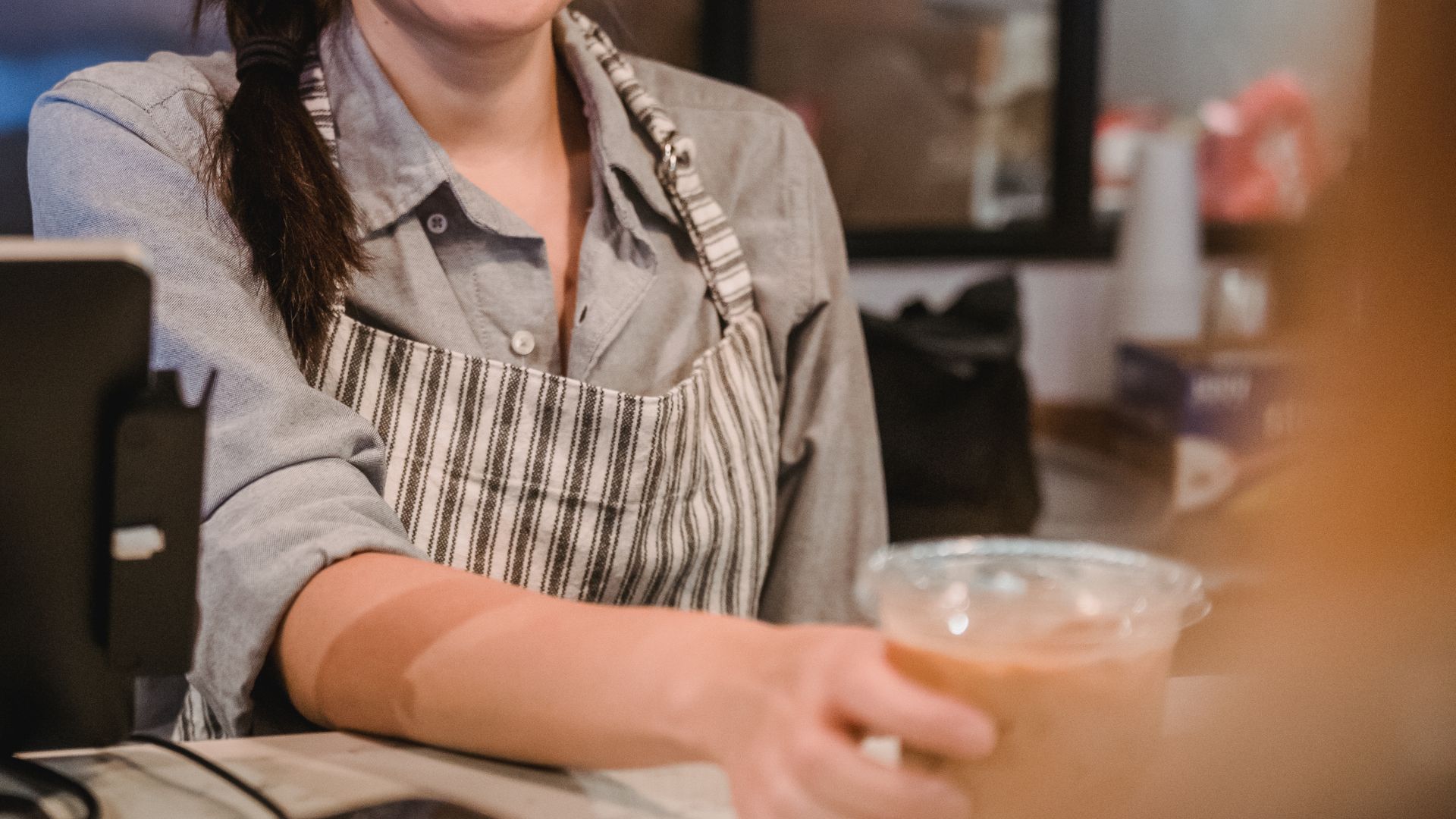 Barista working the counter with a tablet screen beside the coffee