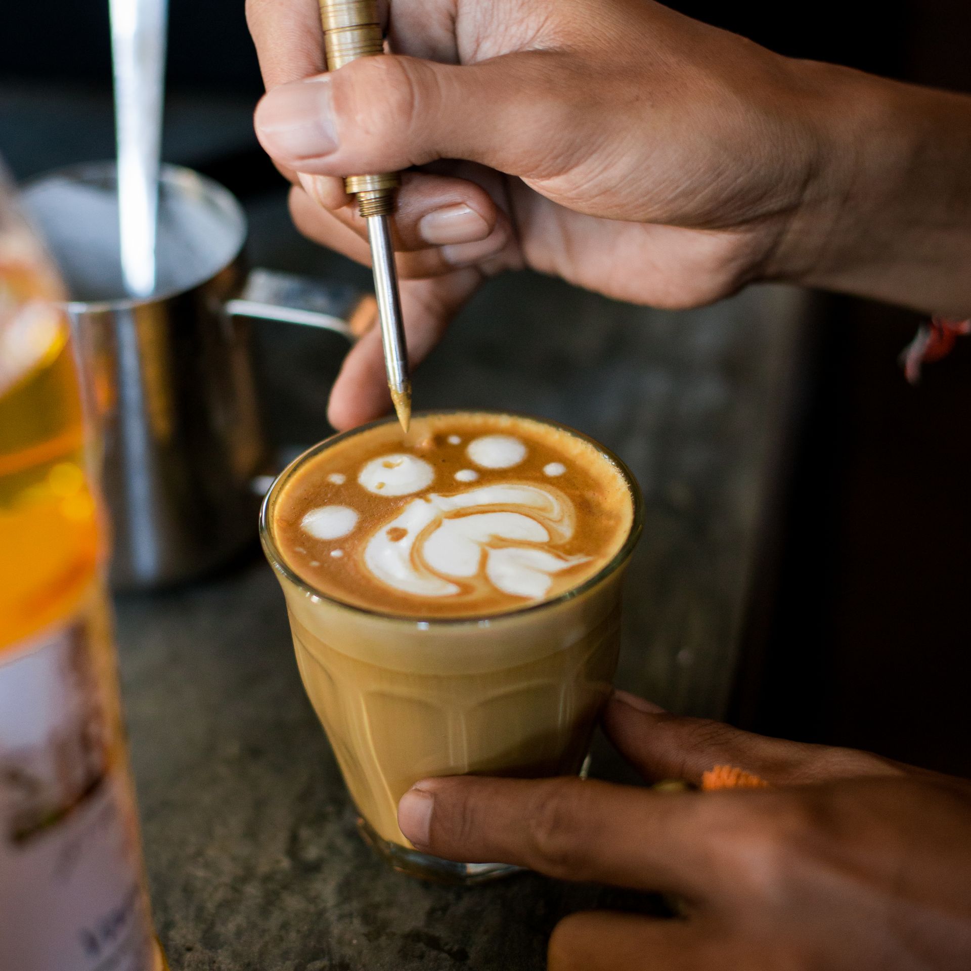 Barista finishing latte art in a glass