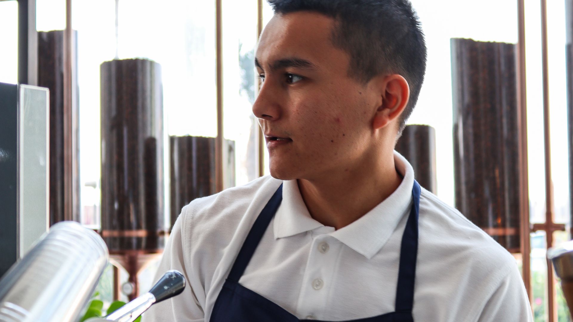 Barista in an apron standing by the café window